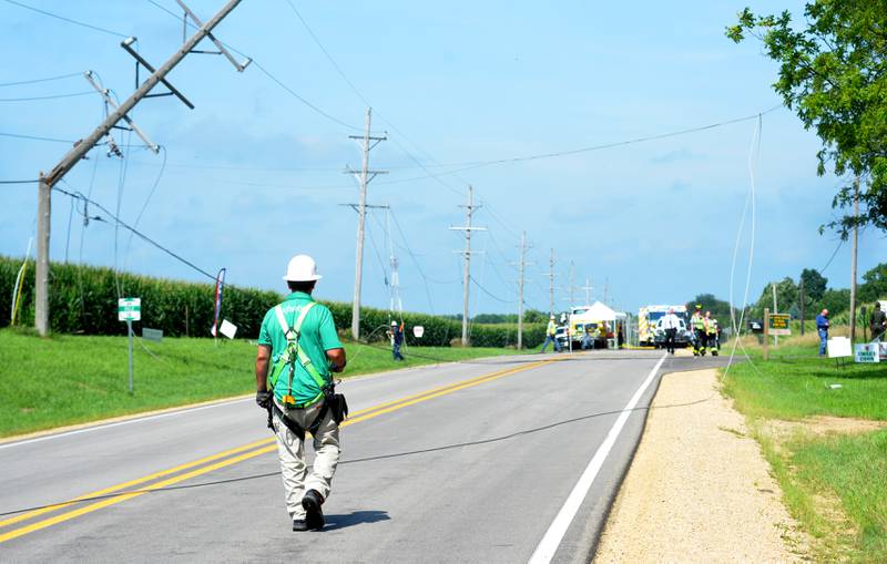 An ComEd worker walks on Illinois Route 64 assessing damage to power lines following a single plane accident near the Ogle County Airport between Oregon and Mt. Morris on Tuesday, July 22, 2025. The pilot of a crop dusting plane was killed. after hitting power lines near the airport. A section of the state highway closed for ComEd crews to repair the damage.