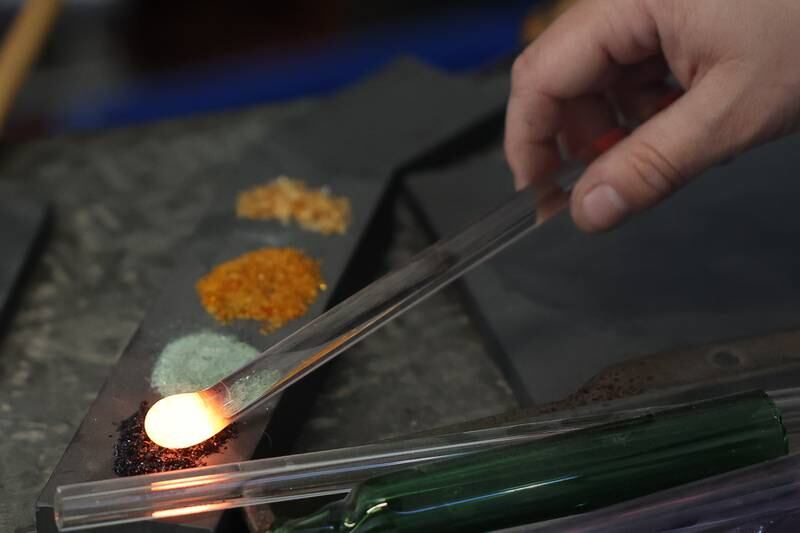 Angelica Cristal uses various colored glass sand on a pendent she is working on. Angelica is opening her own glass art business in the former Regis Glass Art Space in Downtown Joliet.