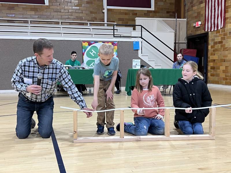 Kendall County Engineer Francis Klaas, along with a few audience volunteers, show how bridges like the new one at Eldamain Road support weight. Klaas spoke to the crowd as part of this year’s 4-H Bridge Bust Contest.