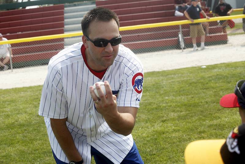 Carmen Pignatiello, a former left-handed pitcher for the Cubs, demonstrates the proper way to grip a baseball during a throwing drill.