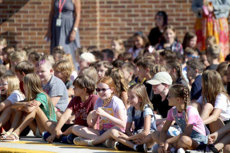 Louise White Elementary School students sit outside as they wait to ring to school’s bell on the first day of school in Batavia on Wednesday, Aug. 16, 2023.