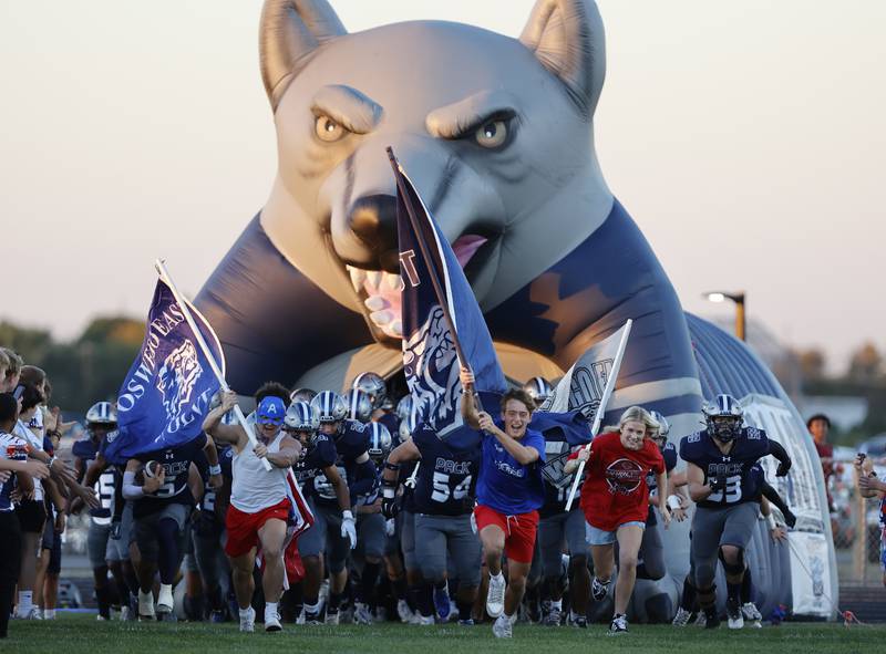 Oswego East's Wolfpack Leaders lead their team onto the field at the varsity football game between Plainfield South and Oswego East on Friday, Sep. 20, 2024 in Oswego.