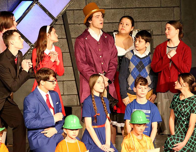 (Back from left) Mr. Salt, played by Cole Vipond, Augustus Gloop, played by Garret Luke, Veruca Salt, played by Maddy Wasilewski, Willy Wonka, played by Mavrick Holocker, Charlie Bucket, played by Seth Sandberg, Mrs. Gloop, played by Mayra Macias, Mrs. Bucket played by Lisa Myres, (Front row) Mr. Beauregarde, played by Ryan Oliver, Violet Beauregarde played by Anna Sandberg, Mike Teavee, played by  Sawyer Smith, Mrs. Teavee, played by Ella Schrowang, and Oompa Loompas Lilly Askeland and Reagan Doehling act out a scene during a performance of Willy Wonka on Thursday, March 16, 2023 at Putnam County High School. The production runs March 23-25. Showtimes are 7p.m. on Thursday and Friday and 2p.m. and 7p.m. on Saturday. Tickets are $10 an adult, students 18 and under and senior citizens are $8.