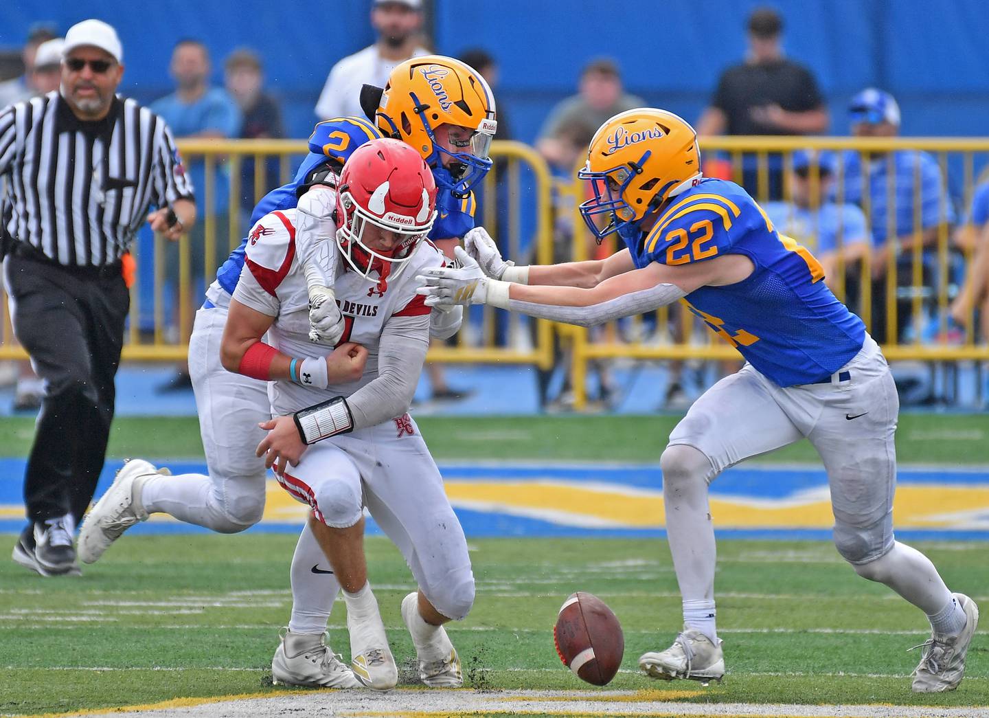 Lyons Township’s Patrick Cheney (top) punches the ball loose from Hinsdale Central quarterback Riley Contreras as Lion teammate Nathan Fitzgerald (22) assists with the stop during a game on September 20, 2025 at Lyons Township High School in LaGrange.