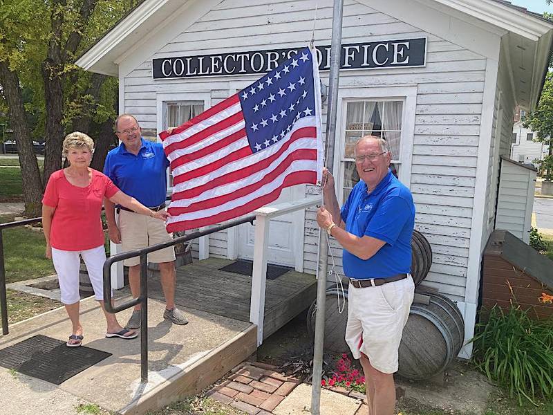 A replica 29-star U.S. flag was raised at the Illinois and Michigan Canal toll collector’s office in Ottawa on Tuesday, July 4, 2023, by (from left) Ottawa Canal Association volunteers Linda Roberts, Bob Eschbach and Arnie Bandstra. The flag was provided by Ottawa Commissioner Brent Barron.