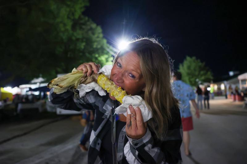 Lori Cortese, of Orland Park, takes a bite of fresh, roasted sweet corn from the Peotone Boy Scout Troop 315 stand the Will County Fair on Aug. 21, 2025. "Who goes to the fair and doesn't get sweet corn?" Cortese pondered.