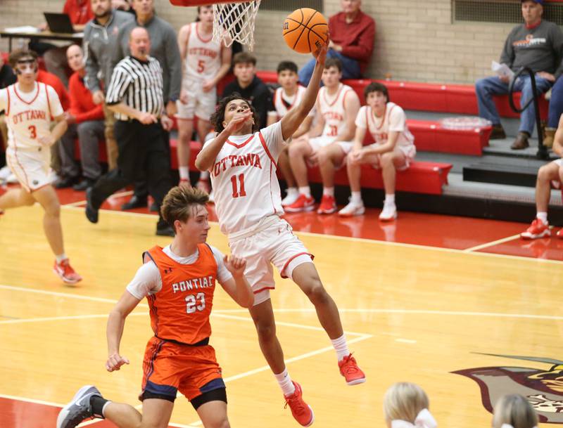 Ottawa's Hezekiah Joachim runs in for a layup over Pontiac's Cayden Masching during the Dean Riley Shootin' The Rock Thanksgiving Tournament on Monday, Nov. 25, 2024 in Kingman Gym at Ottawa High School.