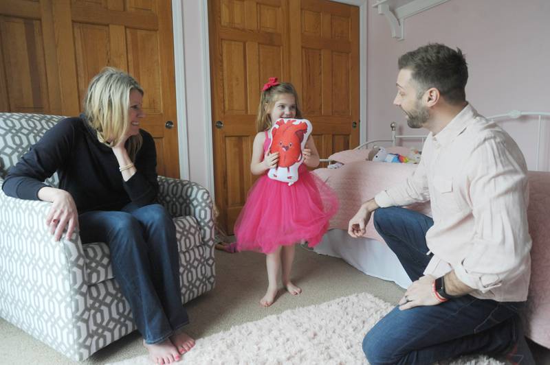 Everly Backe, 4, who has had multiple open heart surgeries to correct congenital heart defects, plays with a heart doll Friday, Feb. 11, 2022, as her parents, Lauren and Matt Backe, watch in their Crystal Lake home. As Everly has became more aware of her chest scar, which they call her "zipper," her dad, Matt, recently decided to go a tattoo that matches his daughter’s scar from her surgeries so she does not feel alone in having the scar.