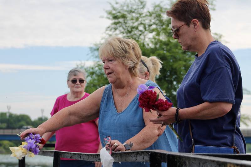 Peggy Buser, accompanied by Christina Young, tosses a flower into the Rock River in memory of Marvin Tubbs of the U.S. Army during. a Memorial Day ceremony, Monday, May 29, 2023.