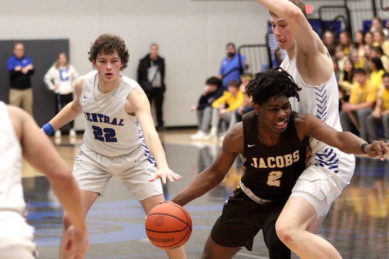 Jacobs’ Treval Howard moves the ball against Burlington Central’s Drew Scharnowski (right) and Nicholas Gouriotis in varsity boys basketball at Burlington Tuesday night.