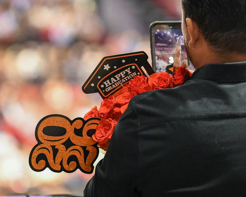 An excited graduation attendee documents some of the ceremony while holding flowers as the St. Charles East  commencement ceremony was in progress on Monday, May 18, 2026, at the Convocation Center in DeKalb.