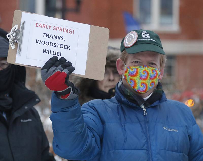 Paul Lockwood holds up a sign after Woodstock Willie made his prognostication of an early spring Wednesday, Feb, 2, 2022, during the annual Groundhog Day Prognostication on the Woodstock Square. This is the 30th anniversary of when the movie “Groundhogs Day” was filmed in Woodstock.