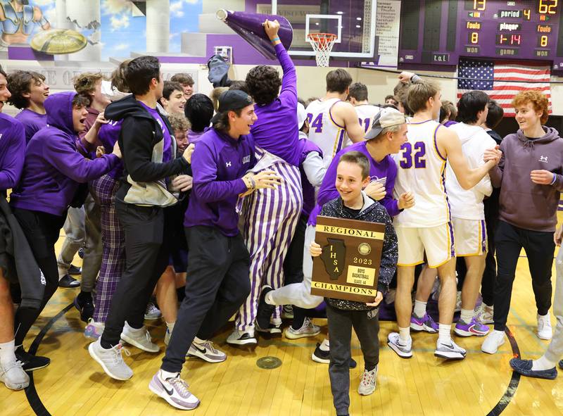 Wyatt Thomas, son of DGN head coach James Thomas, sneaks away with the championship plaque as the team celebrates after the boys 4A varsity regional final between Downers Grove North and Proviso East in Downers Groves on Friday, Feb. 24, 2023.