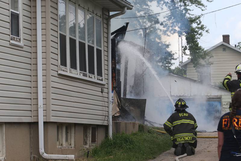 Peru firefighter Pete Ragazinski extinguishes flames from a garage fire in the 800 block of Lafayette Street on Monday, July 22, 2024. The fire began just before 1p.m. La Salle Fire and EMS along with Peru Fire department responded to the call while La Salle Police directed traffic.