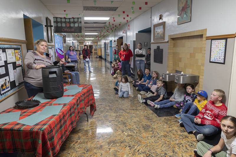 Billie Jo Laidig pulls the first item out of a time capsule Monday, Dec. 23, 2024, opened for the first time in 25 years. Staff and students at Lincoln School in Dixon filled the capsule with the important items. The building now houses the Lincoln Open Sesame Child Care Center.
