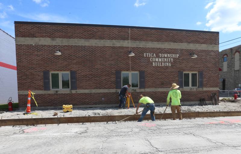 A crew works in front of the Utica Township Community Building near the site of the retail plaza called Market on Mill on Tuesday, Aug. 13, 2024 downtown Utica.