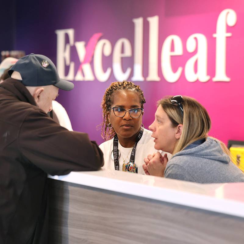 One of the Excelleaf owners Maria Davis (middle) and budtender Jamie Cardenaz help customer Steve Guadagnoli, 79, of DeKalb, Friday, Nov. 24, 2023, during the soft opening of the dispensary in DeKalb. The business is DeKalb County’s first recreational marijuana dispensary.