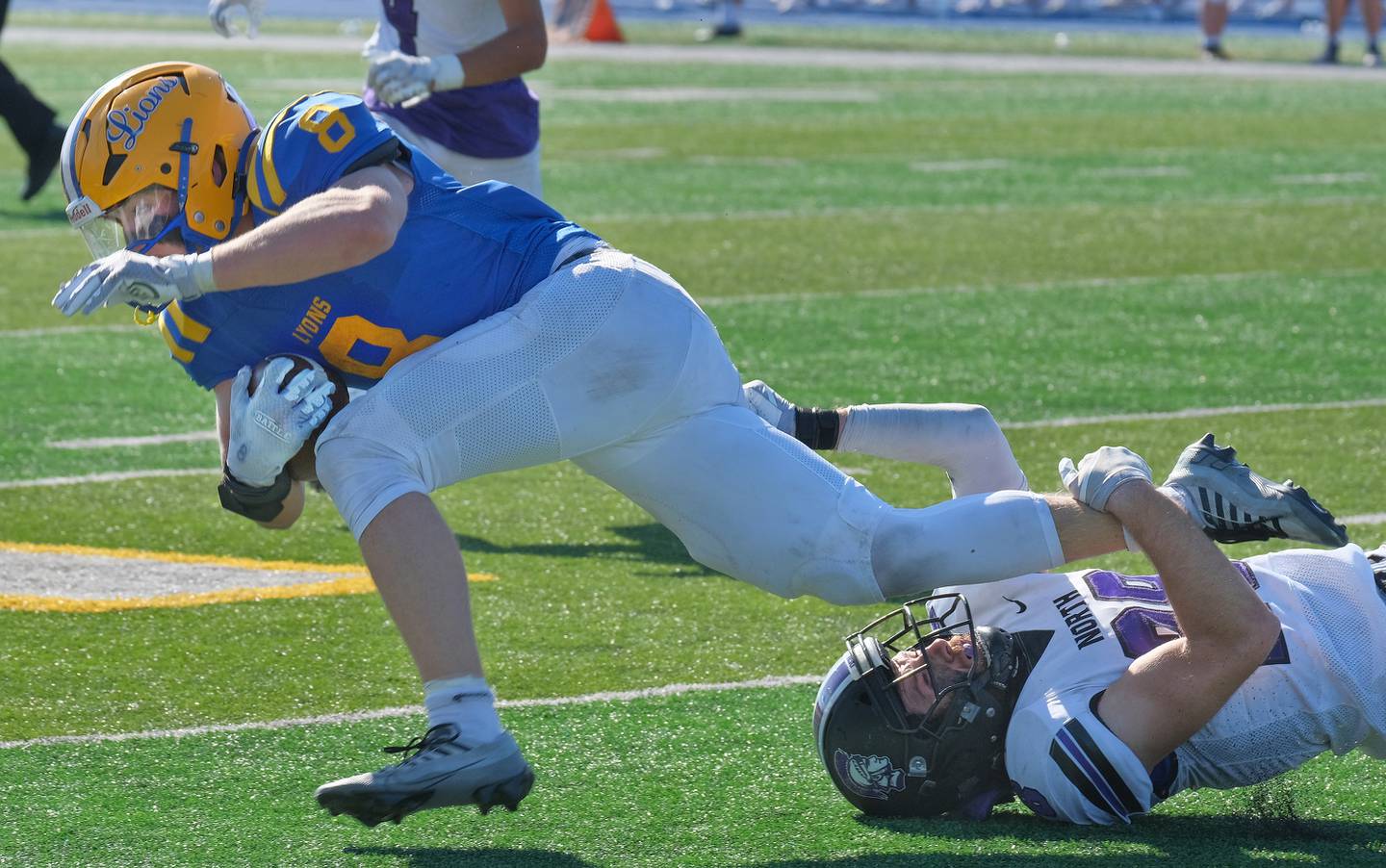 Downers Grove North's Josh Lambert (right) makes a shoestring tackle of Lyons Township's Danny Pasko (8) during a game on Oct. 22, 2022 at Lyons Township High School in LaGrange.