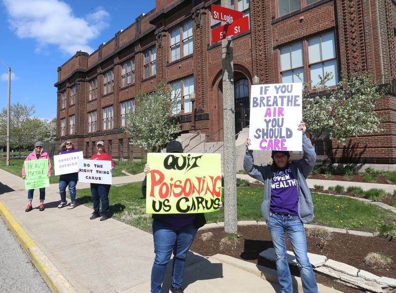 Protesters hold signs while attending the "Protest Carus Negligence" outside Carus headquarters at the corner of St. Louis and 5th Street across from the Westclox building on Friday, April 21, 2023 in Peru.