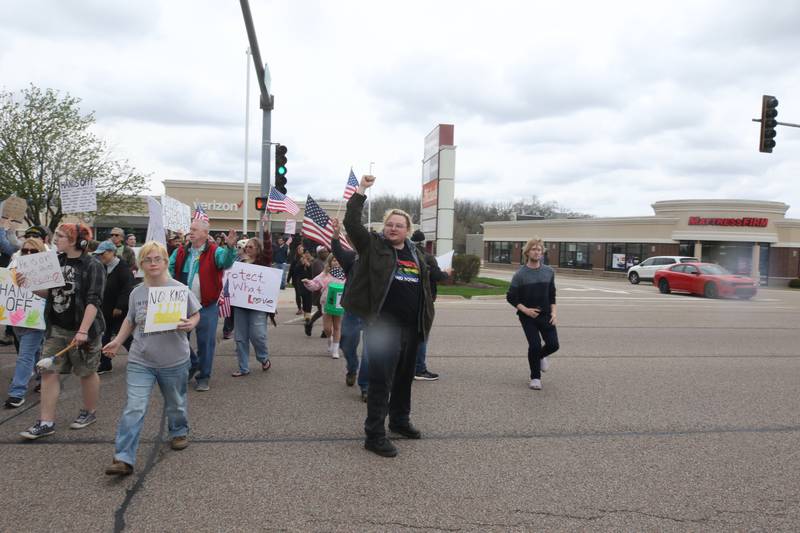 Protesters cross Sycamore Road at Barber Greene Road Saturday, April 19, 2025, during a “No Kings” rally and march in DeKalb. The group was protesting what they’ve argued is the unlawful and harmful federal policies of President Donald Trump and his administration.