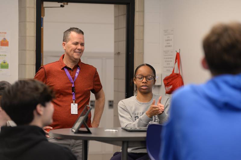 Glenbard East business teacher, Don Prochilo engages with students including Frankie Robinson while she presents her team's product during their business class held Thursday March 16, 2023.