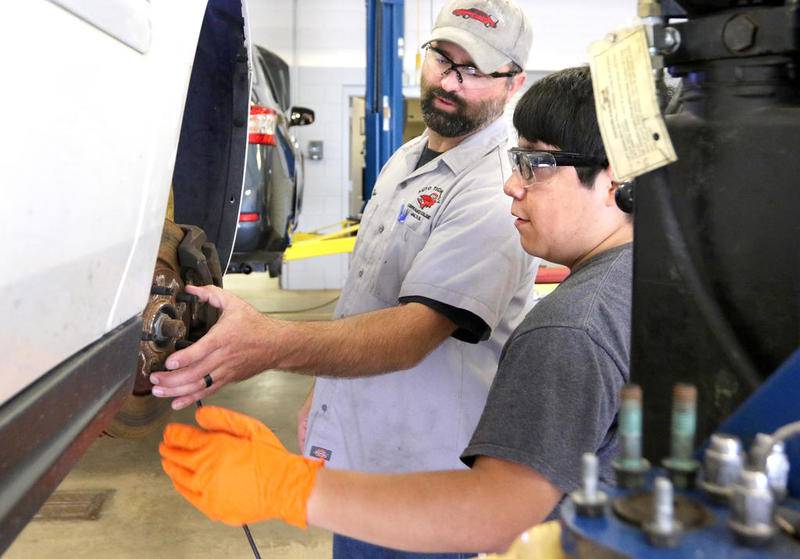 Kishwaukee College instructor Shawn Long (left) shows student Jose Ocelotl, 22, of Genoa, how to loosen the brake calipers from the rotor on a car during an automotive class in this 2019 Shaw Local file photo at the school in Malta.