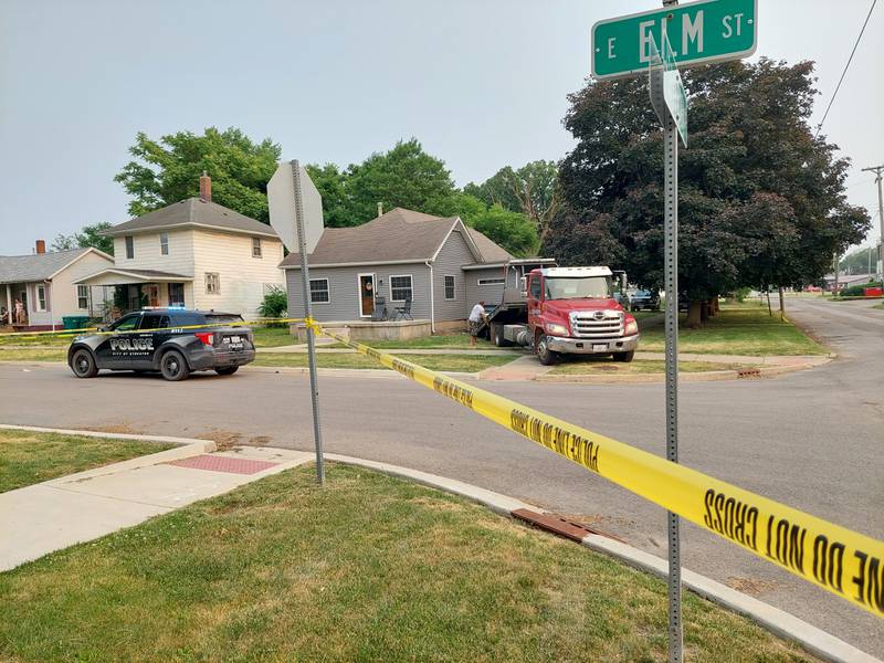 A tow truck removes a vehicle that was involved in a shooting and was crashed into a house at the corner of Elm and Shabbona streets on Sunday, June 4, 2023.