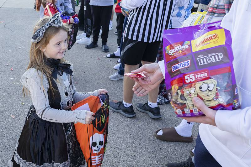 Brynn Temiquel, 6, of Sterling gathers candy from members of the Sterling High School basketball team Wednesday, Oct. 26, 2022.