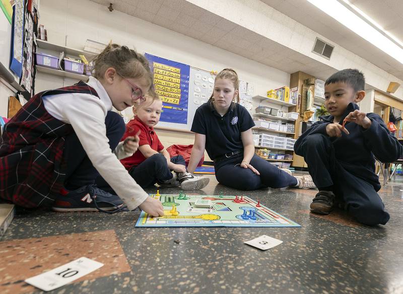 Newman freshman Lauren Dale plays a game of Sorry with Dixon St. Mary’s kindergarteners Anne (left), Brady and Vicente Wednesday, Jan. 29, 2025. NHS students visited the school to play games with the kids in celebration of Catholic Schools Week.