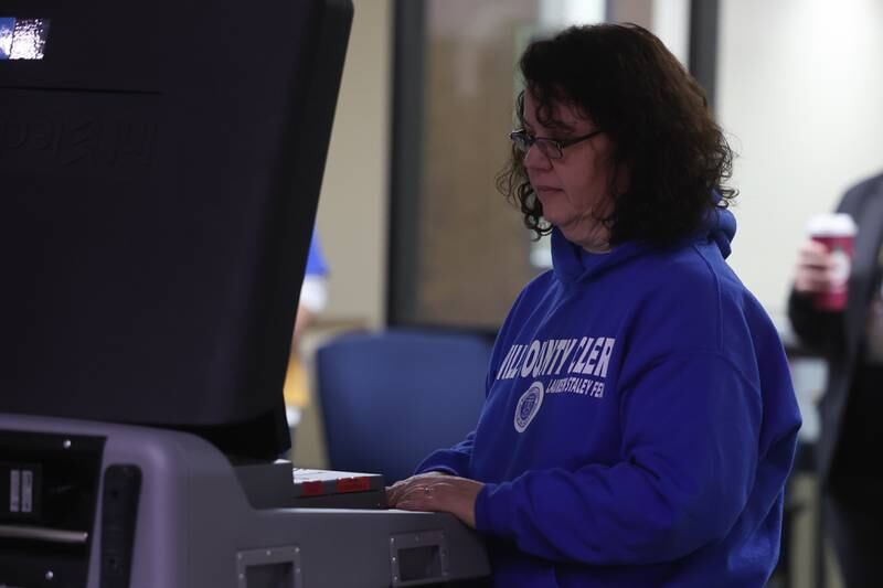 A worker feeds mail in votes into the ballot machine on Tuesday at the Will County Office Building.