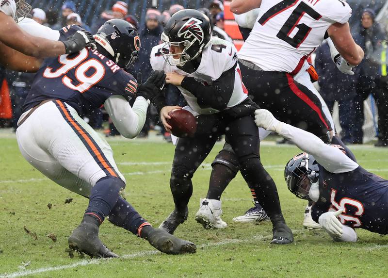 Chicago Bears defensive tackle Gervon Dexter Sr. (left) and defensive end DeMarcus Walker sack Atlanta Falcons quarterback Taylor Heinicke during their game Sunday, Dec. 31, 2023, at Soldier Field in Chicago.