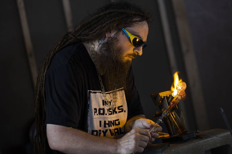 Glass maker Andrew Kauchak works on a piece Saturday, June 28, 2025, during Herbal Root’s CannaFest. All things bud, the cannabis and music fest saw over 50 vendors and hundreds of visitors file into Who Else Land for the third annual event.