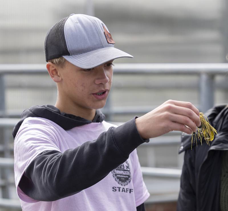 FFA members Denver Sandrock talks about a lure to kids Thursday, May 9, 2024 at the fishing booth at Farmapalooza.