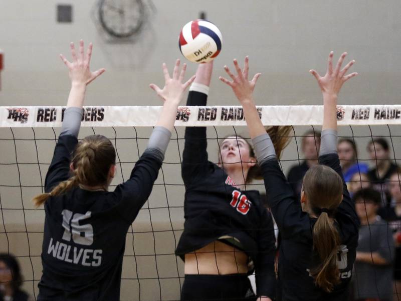 Huntley's Georgia Watson hits the ball between the block of Prairie Ridge's Adeline Grider (left) and Addison Smith (right) during a Fox Valley Conference volleyball match on Tuesday, Oct. 8, 2024, at Huntley High School.