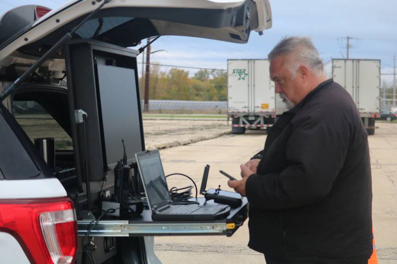 DeKalb Police Department Commander Craig Woodruff takes a look at his phone  Oct. 22, 2025, while preparing a drone to survey the land outside the former GE plant in DeKalb.