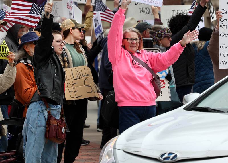 Protesters cheer as passing vehicles honk their horns Saturday, April 5, 2025, as hundreds of people assembled for a Hands Off! rally at Memorial Park on the corner of First Street and Lincoln Highway in DeKalb. The group gathered to protest against various policies of President Donald Trump and his administration.