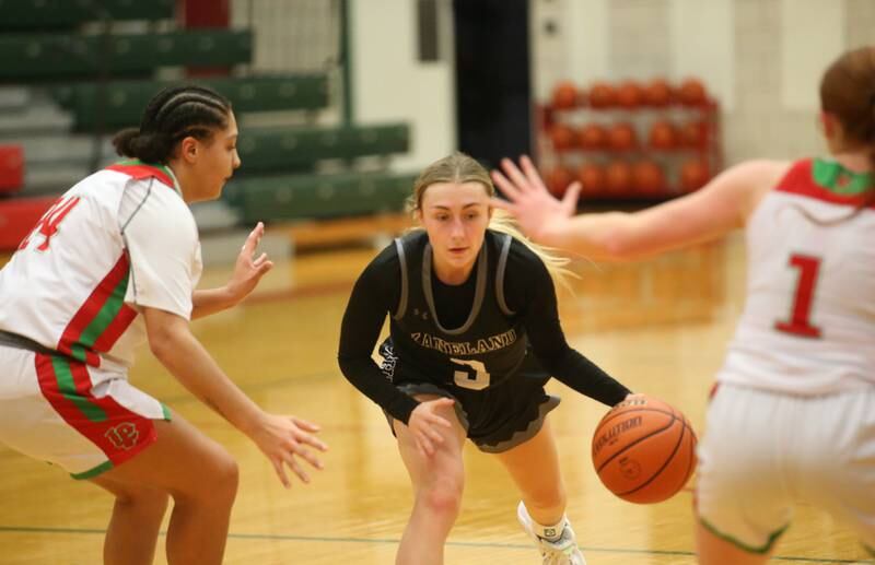 Kaneland's Alexis Schueler dribbles between L-P defenders Jasmine Garman and teammate Addison Duttlinger on Friday, Dec. 8, 2023 in Sellett Gymnasium at L-P High School.