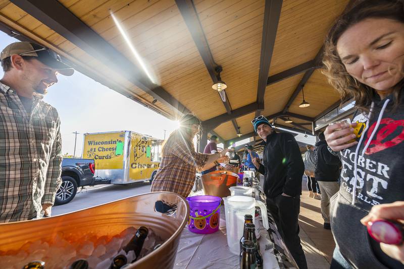 Stephanie Jacobs (middle), a volunteer from Sauk Valley College, pours James Schudlt of Rock Falls a drink Saturday, Oct. 8, 2022 at Sterling Main Streets Hops on the Rock. Jacobs excitedly signed up to volunteer at the event.