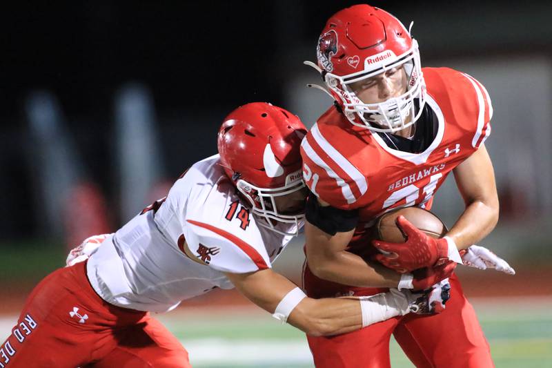 Naperville Central's Tyler Dodd (21) is tackled by Hinsdale Central's Gavin Vande Lune (14) during football game between Hinsdale Central at Naperville Central.  August 26, 2022.