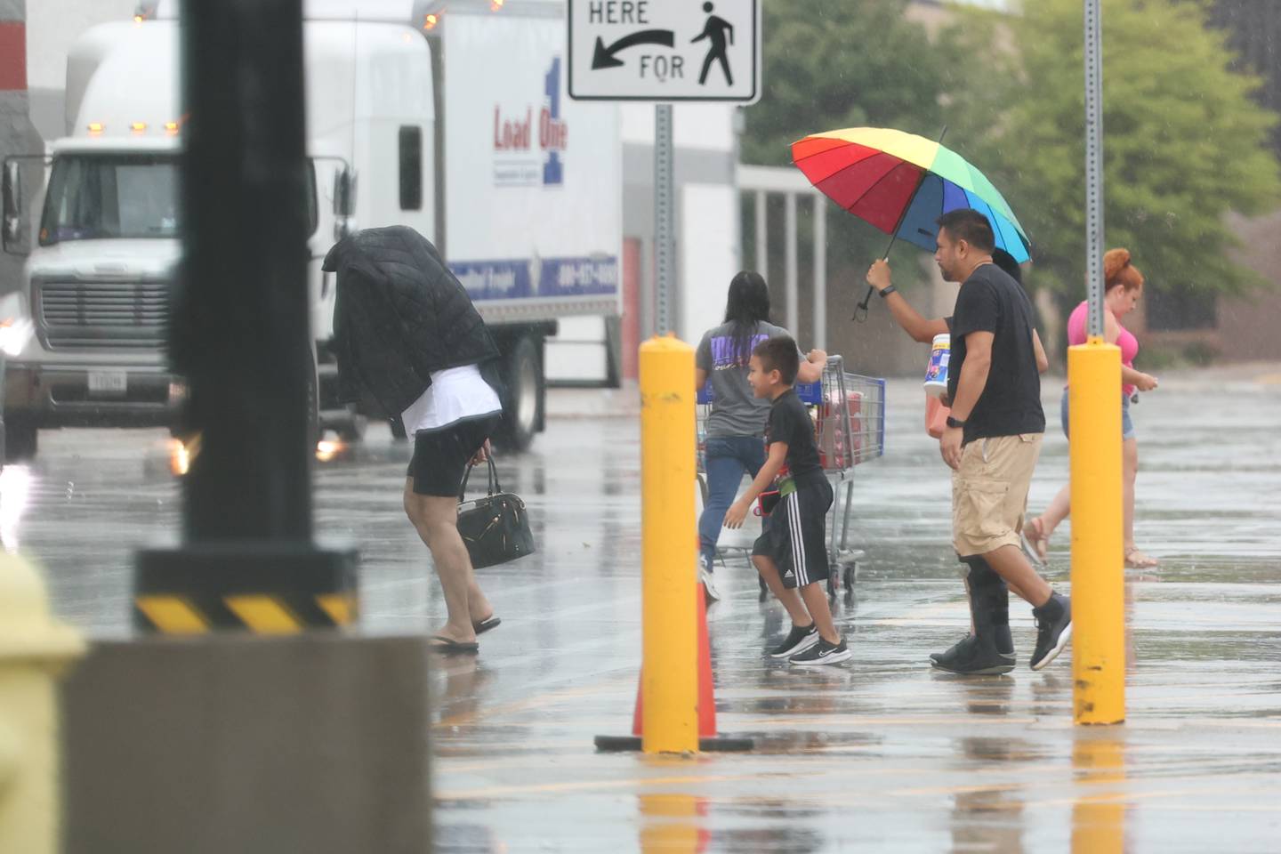 A family walks through a parking lot during the rain in Joliet. Monday, Aug. 29, 2022, in Joliet.