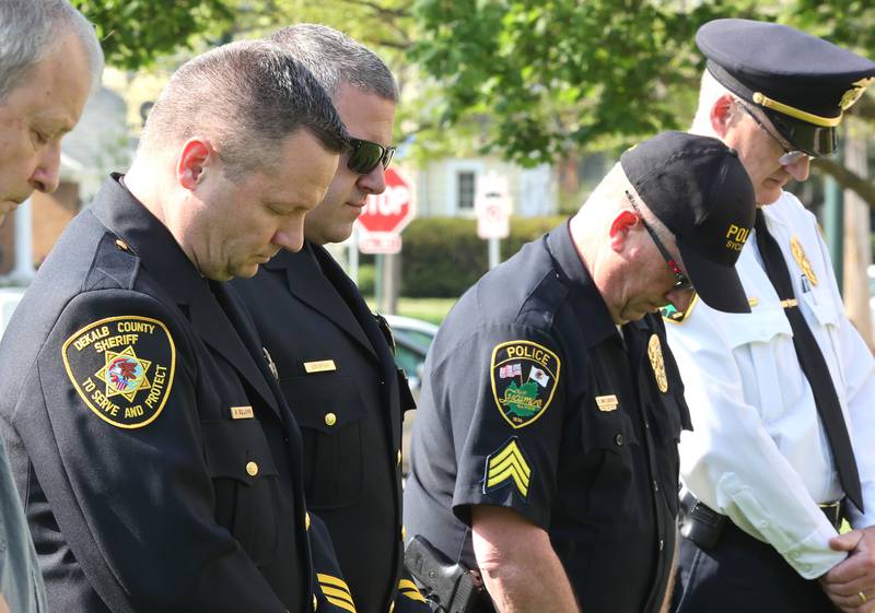 DeKalb County Sheriff Andy Sullivan, (left) along with other area law enforcement personnel, bow their heads in prayer Friday, May 13, 2022, during the DeKalb County Law Enforcement Officers' Memorial Service on the lawn of the DeKalb County Courthouse in Sycamore.
