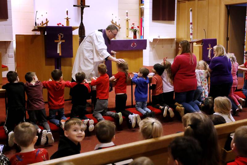 Rev. Mark Buetow, of the Zion Evangelical Lutheran Church in McHenry, blesses a student from the church's preschool on Wednesday, Feb, 14, 2024, during a service for the students and church members on Ash Wednesday.