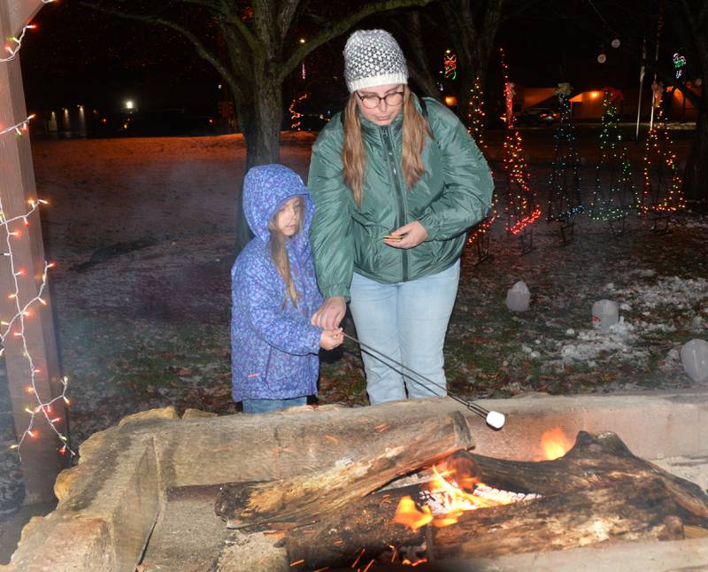 Brooke Oulbey helps Arianna Rowe, 7, of Forreston, toast a marshmallow for her S'more at Memorial Park during Forreston's Christmas in the Country on Friday, Dec. 1, 2023.