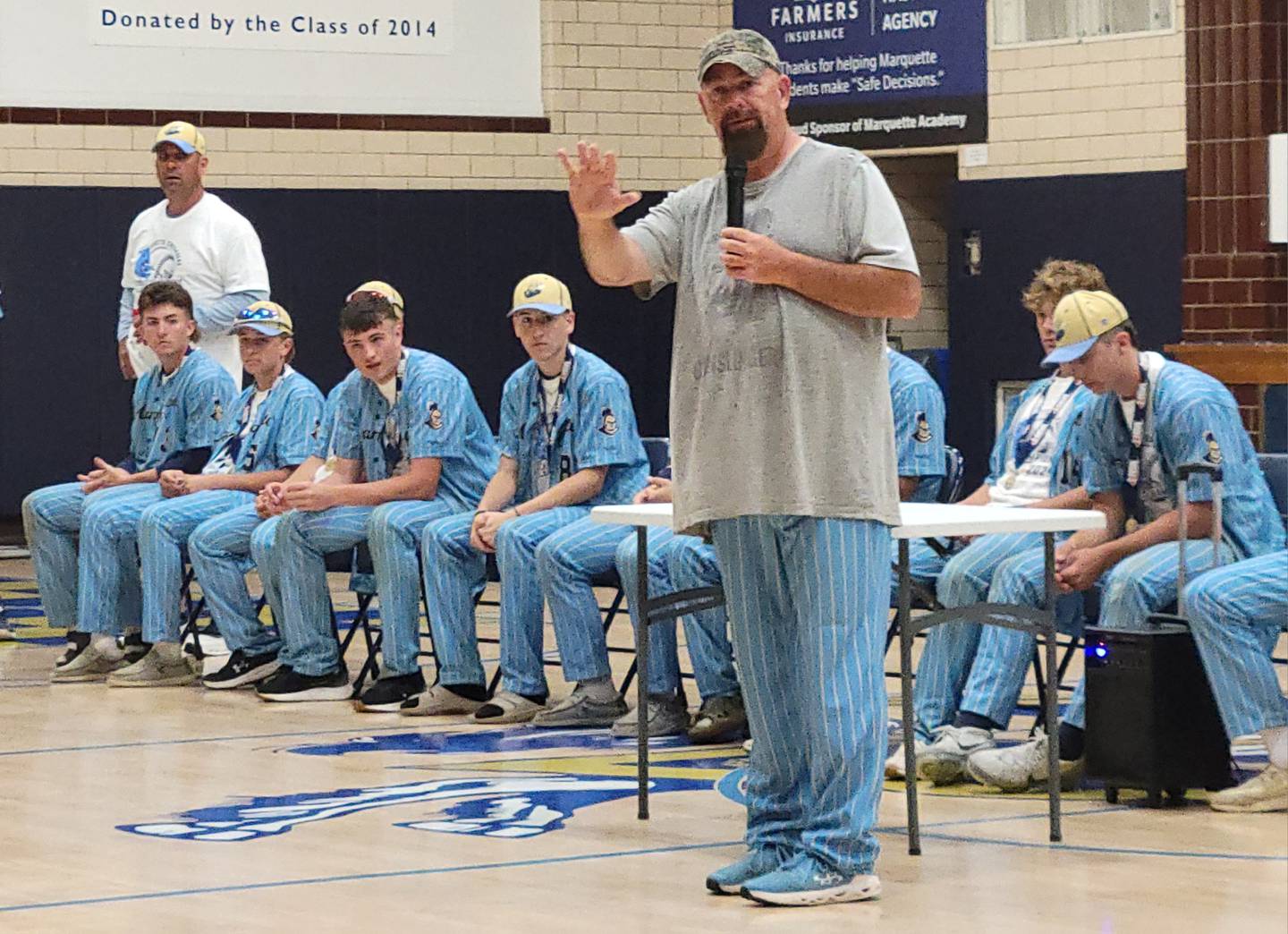 Marquette head coach Todd Hopkins addresses his team and the crowd at the welcome home assembly at Bader Gym on Saturday.