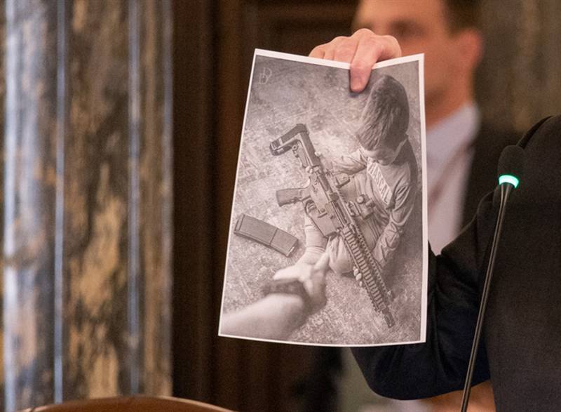 Senate President Don Harmon, D-Oak Park, pictured in May, holds up an ad from the company Wee 1 Tactical, maker of the JR-15 rifle, a gun that resembles an AR-15 rifle but is smaller and lighter, making it easier for children to fire.