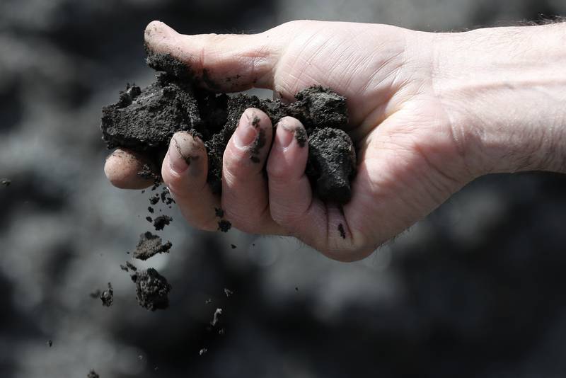 Fox Waterway Agency Executive Director Joe Keller crumbles some nutrient-rich sediment in his hands at the agency's Cooper Farm Sediment Dewatering Facility on Tuesday, April 13, 2021, in Antioch.