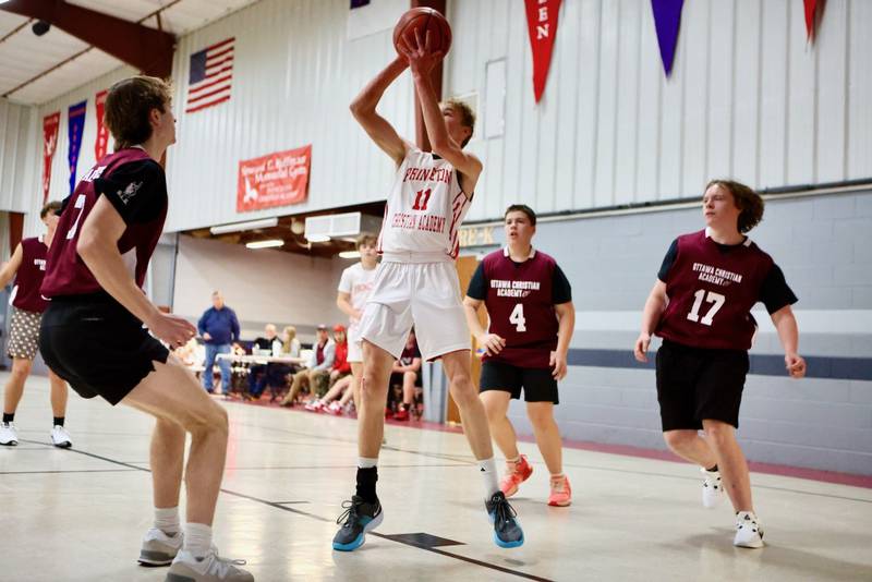 Princeton Christian Academy's Andrew Gibson takes aim against's Ottawa Christian Academy's Brody Pagakis (left), Ashton Gonzalez (4) and Jackson Poggi (17) Tuesday at Howard Hoffman Memorial Gym. The Eagles won 57-42.