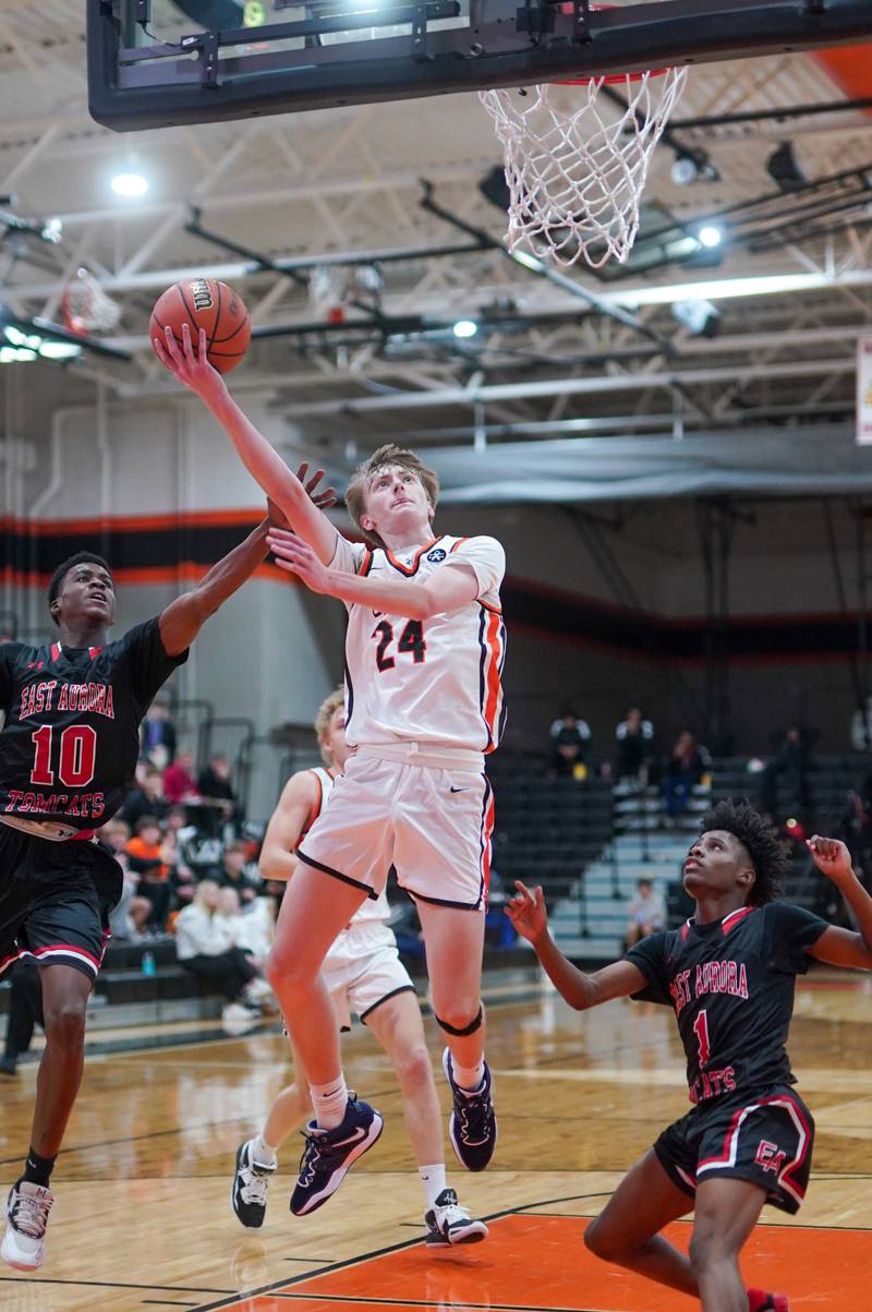 St. Charles East's Andrew Wolfsmith (24) plays the ball in the post against East Aurora's Davion Tidwell (10) and Jaheim Wilkins (1) during the 64th annual Ron Johnson Thanksgiving Basketball Tournament at St. Charles East High School on Monday, Nov 20, 2023.