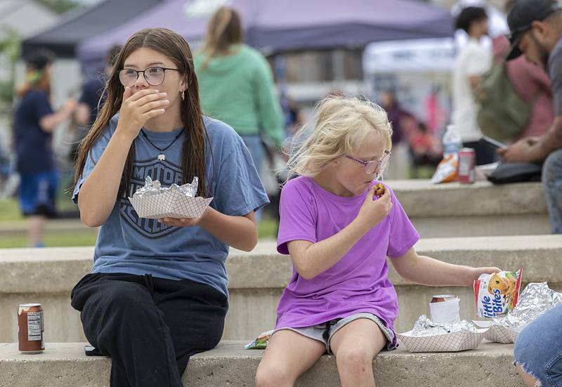 Cherikee Serenil, 15, and Kiyla Scott, 9, of Rock Falls chow down on a snack Tuesday, Aug. 6, 2024 during National Night Out.