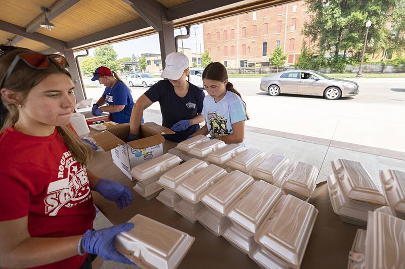 Brittany Whitman (left), working with the Impact Program at Sauk Valley Community College, volunteers Monday, July 24, 2023, at the Rotary Club’s Corn Boil and BBQ Pork Chop sale.